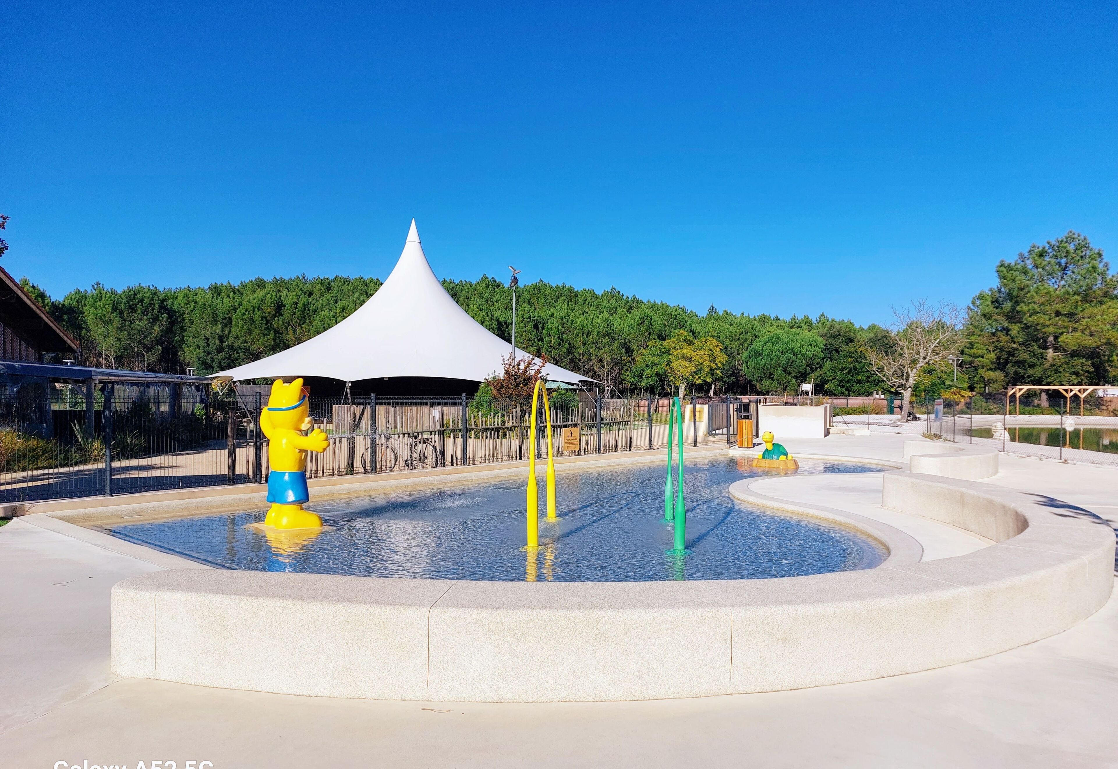 A water play area with a white tent and a yellow and blue water feature.