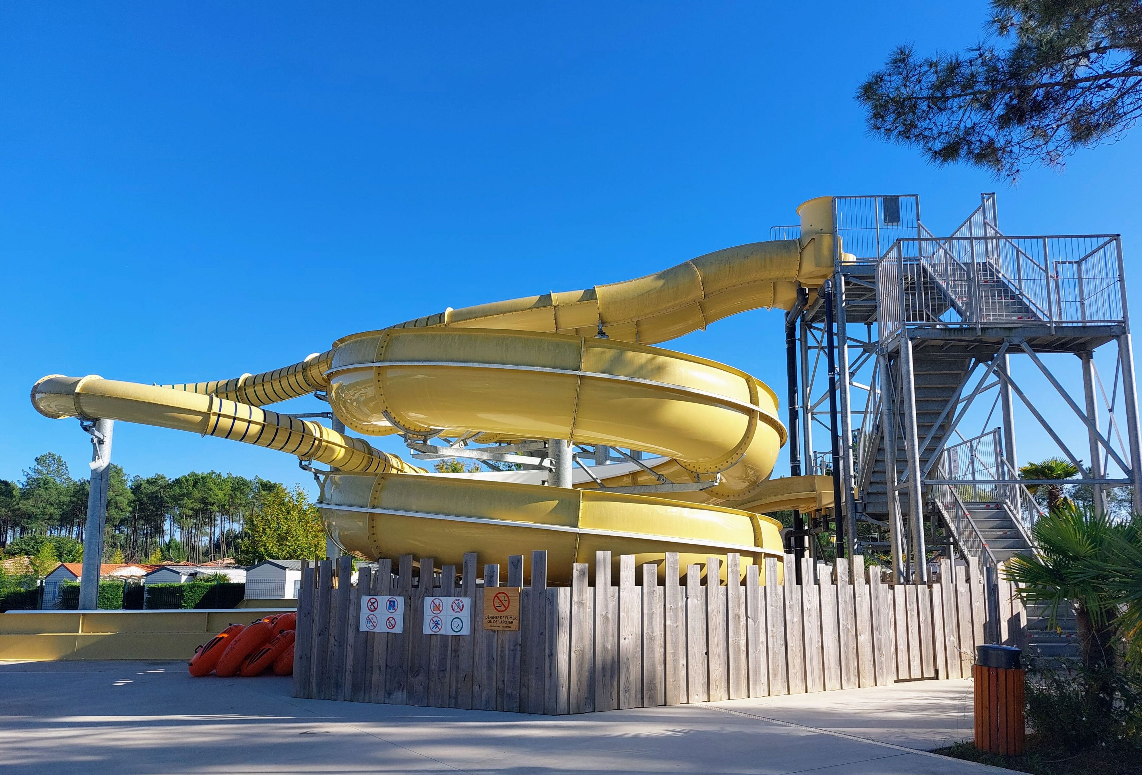 Une grande structure de toboggan aquatique, dotée d’une clôture en bois et d’un escalier en métal.