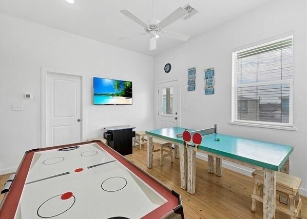 A room with a pool table, ping pong table, and a ceiling fan. - Feelin' Tip-Sea -Short Walk to Sandfest! Pets, Pool ,Game Room, & Boat Parking! (Port Aransas)