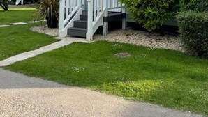 Une maison à deux étages avec un porche à l’avant, un escalier et une pelouse bien entretenue.