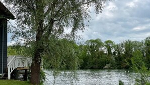 Une vue sur le lac, avec un quai en bois, une zone herbeuse et des arbres.