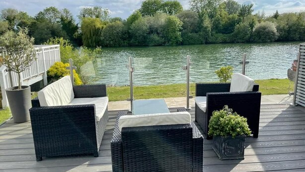 Une terrasse dotée de meubles en osier et offrant une vue sur un lac.