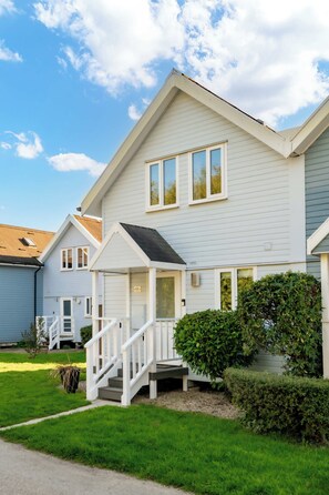 A two-story residential house with a front porch, a staircase, and a well-maintained lawn.
