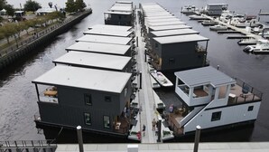 Eine an einem Steg festgemachtes Hausboot mit einer überdachten Terrasse, einer kleinen Außenlounge und einer Treppe, die zum Oberdeck führt.