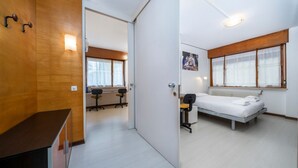 A modern room with a bed, desk, and chair, a wooden wardrobe, and a large window. - GuestHost - Udine's Heart Apartment (Udine)