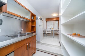A compact kitchen with a double sink, a refrigerator, and a dining area with a table and chairs. - GuestHost - Udine's Heart Apartment (Udine)