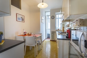 Une cuisine équipée d’une table à manger, de chaises, d’une horloge et d’un four à micro-ondes.