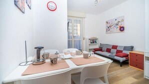 Una sala de estar moderna con un sofá, una mesa de comedor con sillas, una cafetera y obras de arte en las paredes.