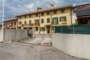 A row of yellow buildings with green shutters, a gated entrance, and a clear sky. - Leisure & Business (Buttrio)