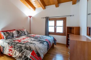 A bedroom with a bed, a wooden dresser, a window with curtains, and a sloped ceiling. - Leisure & Business (Buttrio)