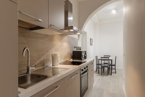 Une cuisine moderne équipée d’une cuisinière, d’un four et d’un évier intégrés. On y trouve également un coin repas avec une table et des chaises.