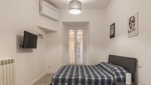 Une chambre à coucher avec un lit, une télévision, un radiateur et une fenêtre.