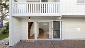 Een twee verdiepingen tellend huis met een balkon, een garage en een zichtbare trap naar de bovenverdieping.