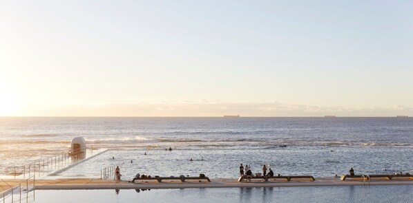 A pool area with a view of the ocean and ships in the distance. - The Breeze - holiday apartment in Merewether, Newcastle (Merewether)