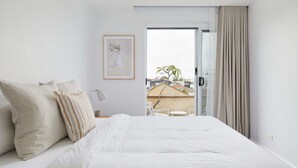 A modern bedroom with a large bed, a framed picture on the wall, and a view of the outside balcony. - The Breeze - holiday apartment in Merewether, Newcastle (Merewether)