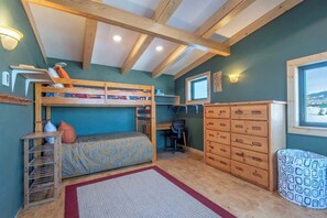 Una habitación con literas, escritorio, silla y espacio de almacenamiento.