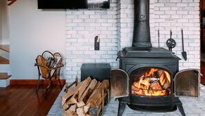 Ein Wohnzimmer mit Kamin, einem an der Wand montierten Fernseher und einer Treppe, die nach oben führt.
