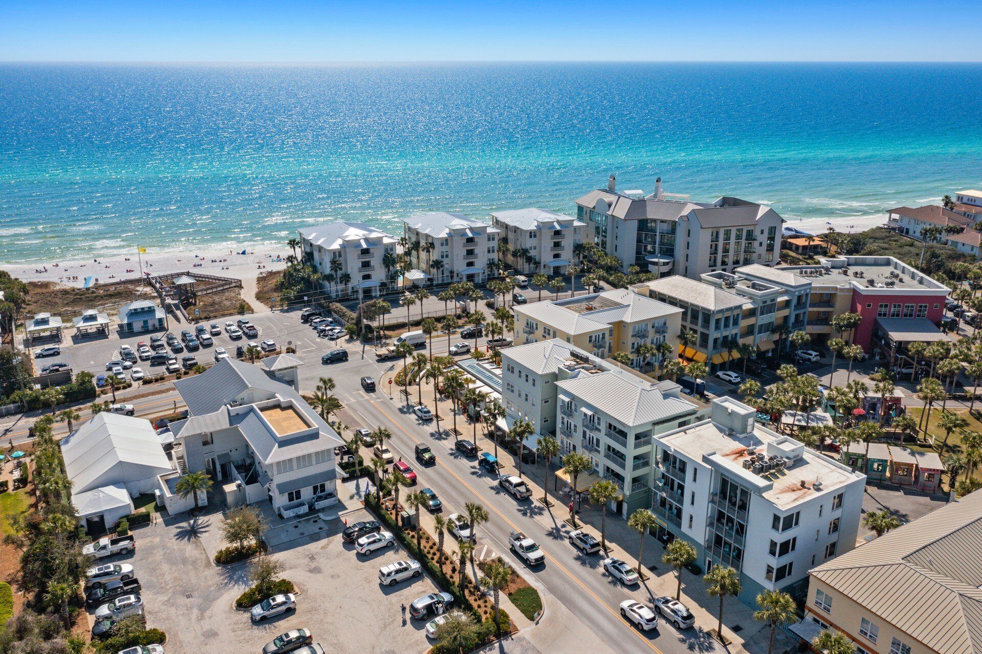 Vogelperspektive eines Hotelkomplexes an der Küste, mit mehreren Gebäuden, einem Parkplatz und einem Strand im Hintergrund.