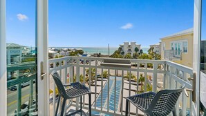 Un balcon avec deux chaises, une piscine et une vue sur l’océan et les bâtiments.