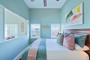 A bedroom with a bed, two windows with blinds, a ceiling fan, and a painting on the wall. - CUTE! Soak in Gulf Views and (Santa Rosa Beach)
