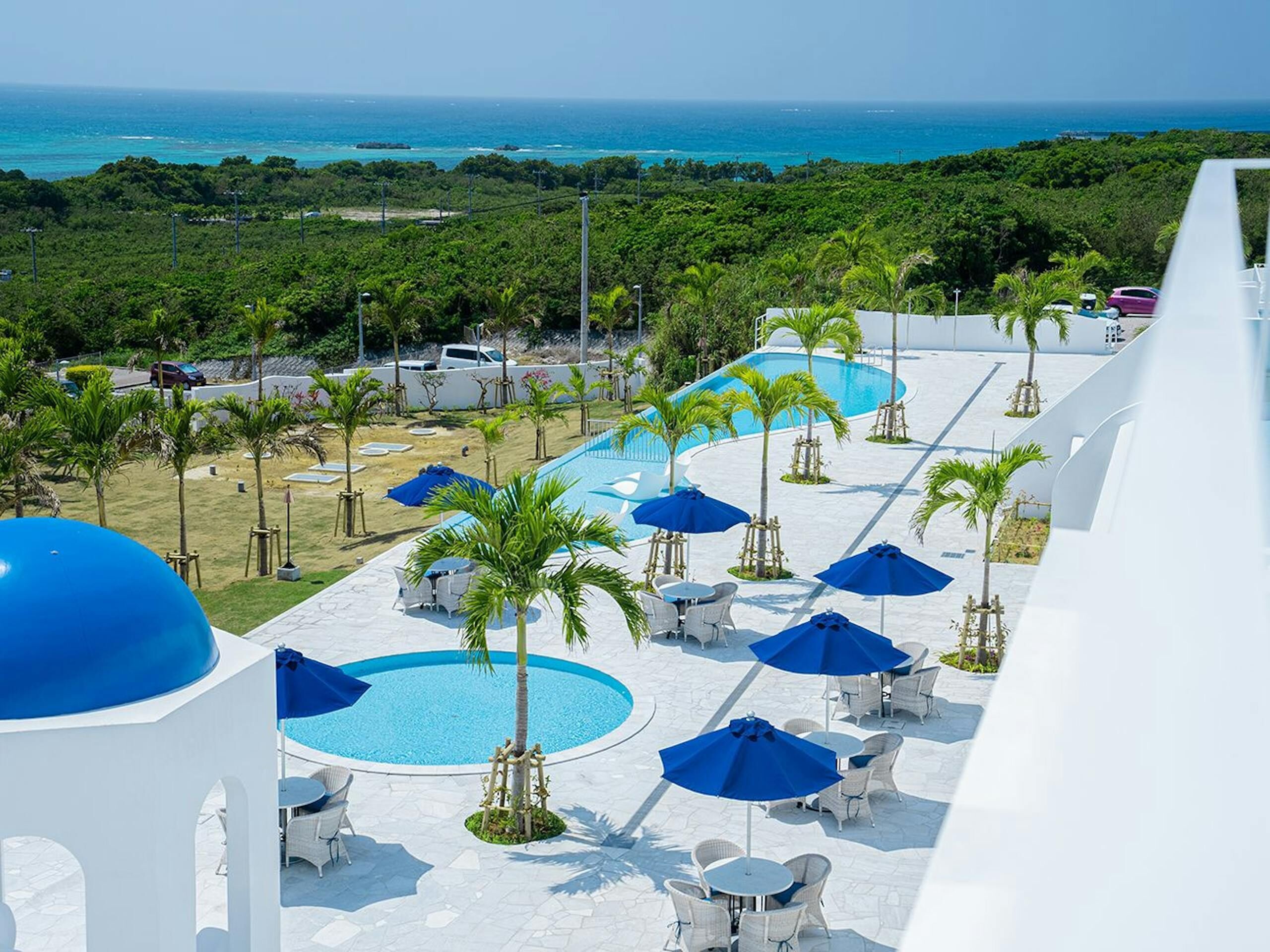 Un resort con zona de piscina, mobiliario exterior y vistas al océano.