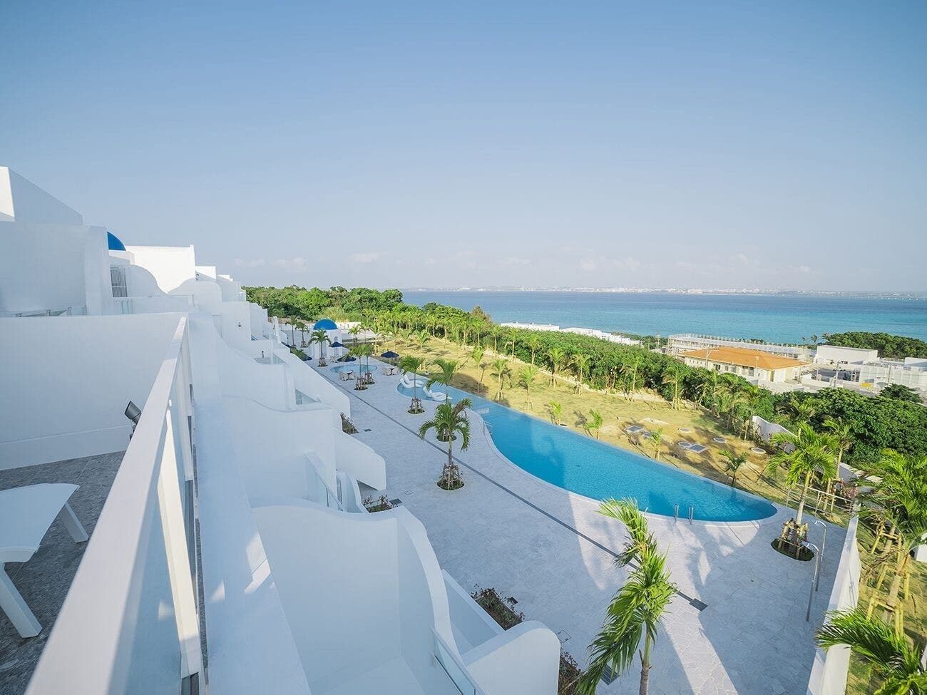 Un complexe hôtelier doté d’une grande piscine, de bâtiments blancs et offrant une vue sur la mer.