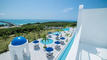 Een resort met een zwembad, ligbedden en parasols, met uitzicht op een strand en de oceaan.
