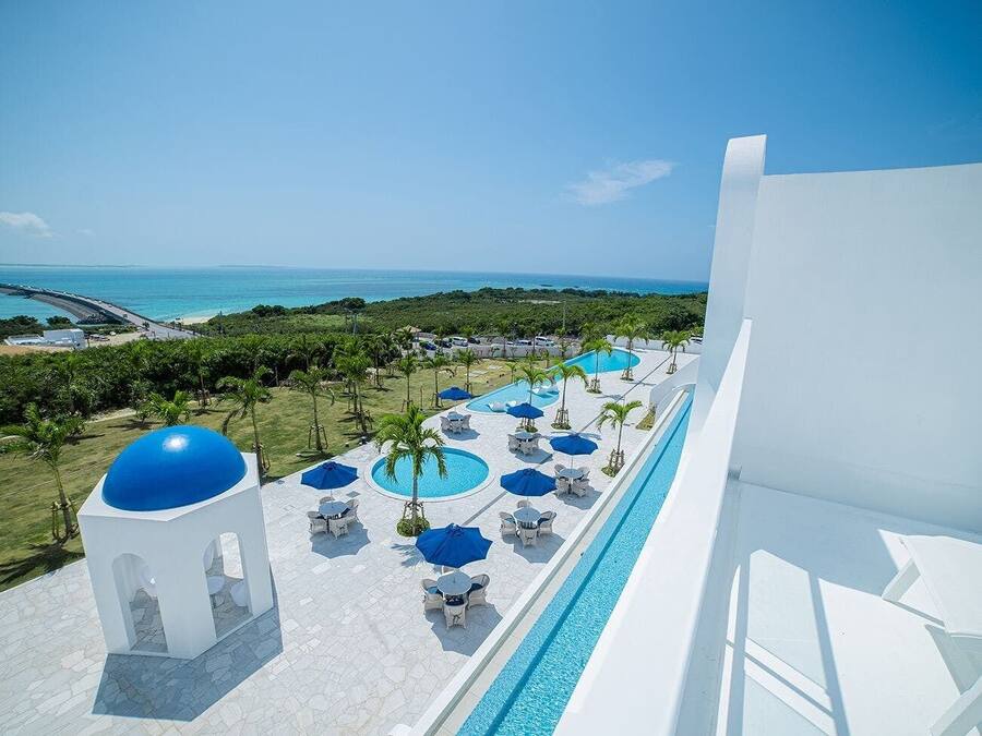 Een resort met een zwembad, ligbedden en parasols, met uitzicht op een strand en de oceaan.