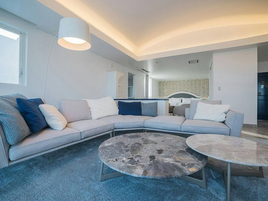 A modern living room with a sectional sofa, two round coffee tables, and a large floor lamp.