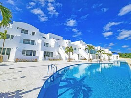 Un edificio moderno blanco con piscina y palmeras.