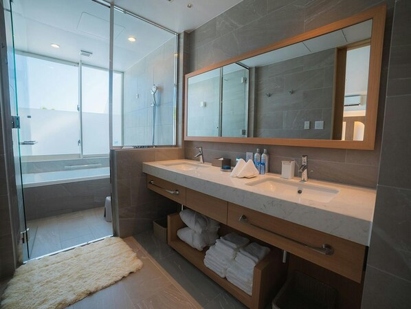 A modern bathroom with a glass shower enclosure, dual sinks, and a large mirror.