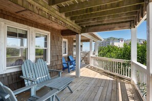 Eine Holzterrasse mit Adirondack-Stühlen und einem weißen Geländer.