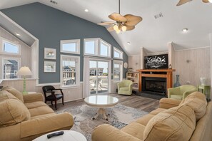 Un salon spacieux avec un haut plafond, de grandes fenêtres et une cheminée.