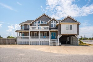 Une maison à deux étages avec un balcon, un garage et une véranda à l’avant.