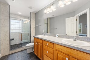 A modern bathroom with a glass shower enclosure, two sinks, and wooden cabinetry.