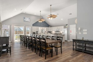 Une cuisine spacieuse avec des meubles blancs, une table à manger en bois et un ventilateur de plafond.