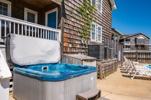 A backyard with a hot tub, outdoor furniture, and a wooden fence. - Sea You Soon: Semi-Oceanfront, Private Pool, Dog Friendly, Hot Tub and Game Room! (Southern Shores)