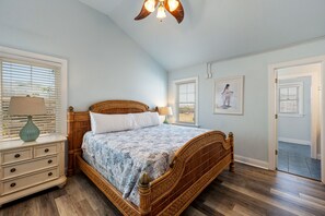 A bedroom with a large bed, a nightstand, a lamp, and a ceiling fan. - Sea You Soon: Semi-Oceanfront, Private Pool, Dog Friendly, Hot Tub and Game Room! (Southern Shores)