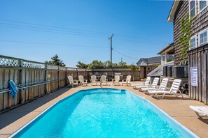 Ein rechteckiger Pool mit Liegestühlen und einem Holenzaun.