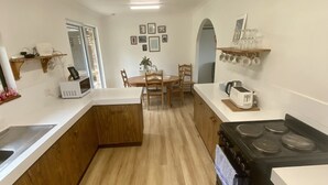 Une cuisine moderne avec un plancher en bois, des comptoirs blancs, une cuisinière et un coin repas avec des chaises.