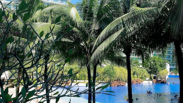 Un complexe hôtelier doté d’une piscine, de palmiers et d’un grand bâtiment en arrière-plan.