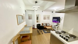 Une cuisine compacte équipée d’une cuisinière, d’un four à micro-ondes et d’un coin repas avec des chaises et une table.