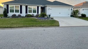 A single-story house with a garage, a well-maintained lawn, and a driveway.
