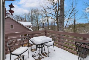 A covered outdoor area with a table and chairs, a lantern, and a view of trees and a house in the background. - Beautiful Townhome in Private Community (Boone)