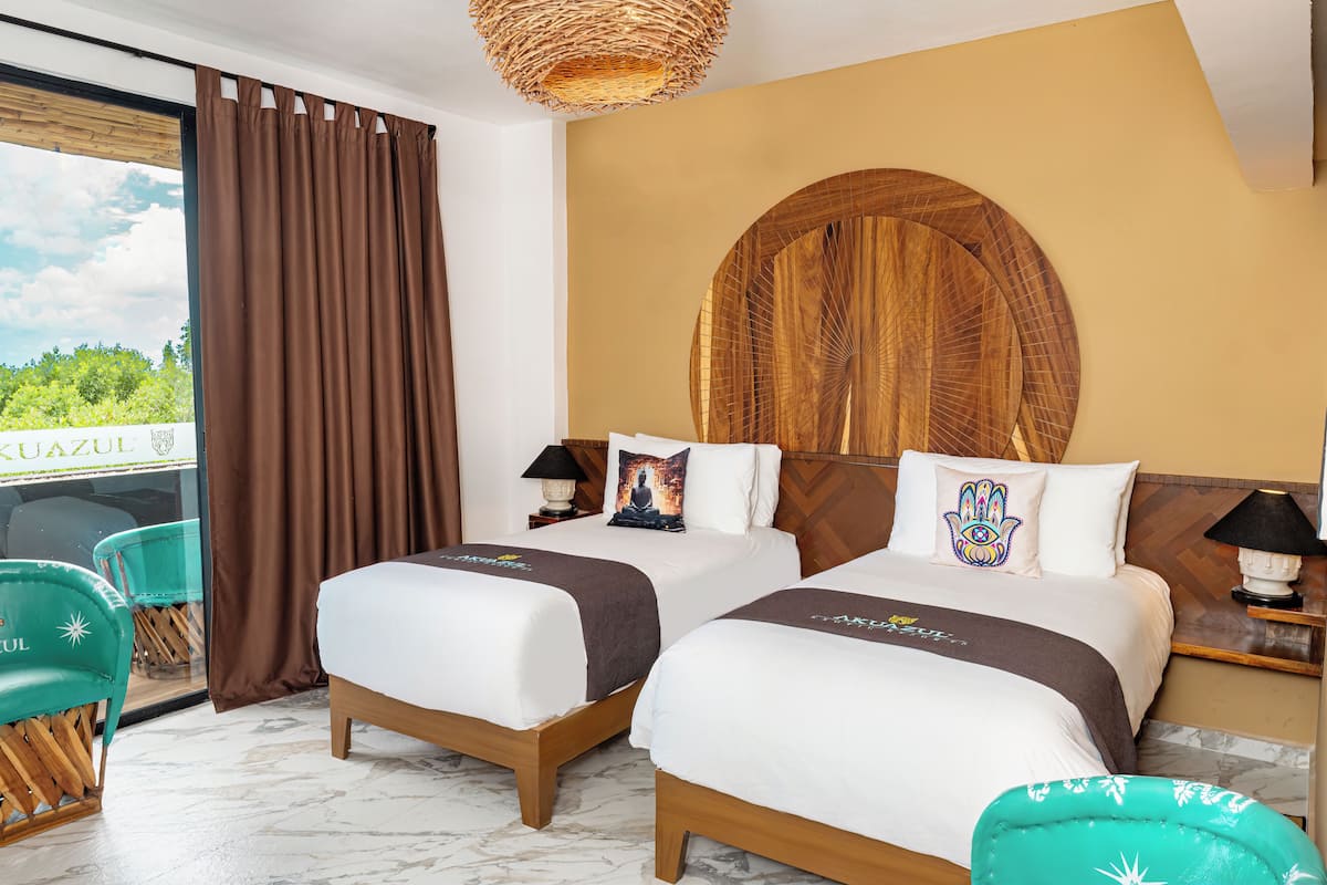 Een hotelkamer met twee bedden, een grote houten wanddecoratie, uitzicht op groen en een rieten plafondlamp.