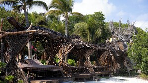 Un complexe hôtelier en bord de mer, doté d’espaces de détente avec toits de chaume et d’une structure rustique en bois.