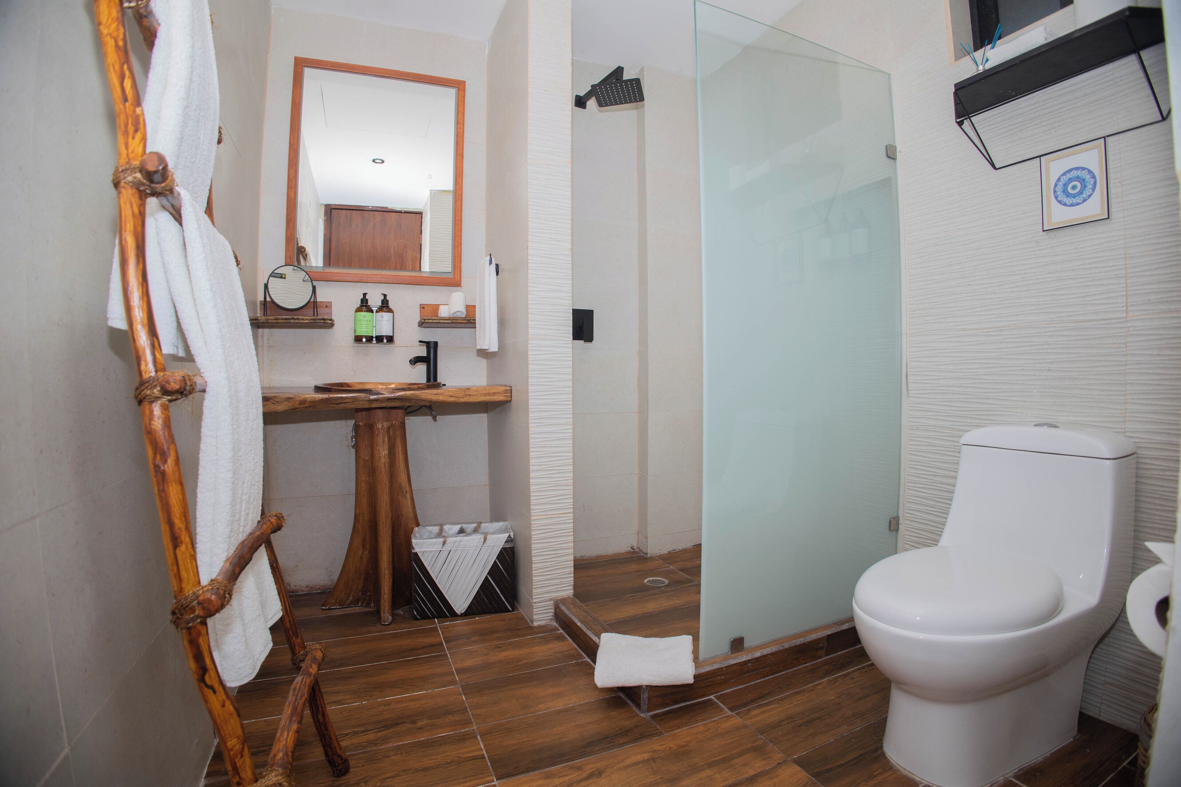 A bathroom with a wooden vanity, a white toilet, and a glass shower enclosure.