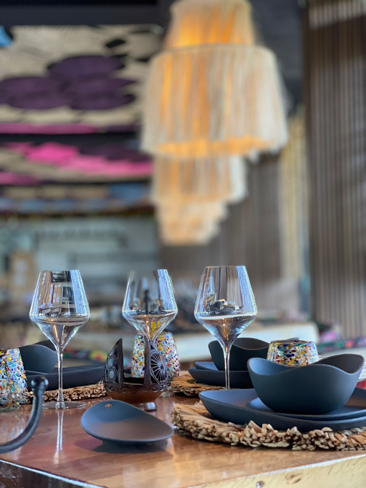 A dining table set with wine glasses, bowls, and a decorative lamp.