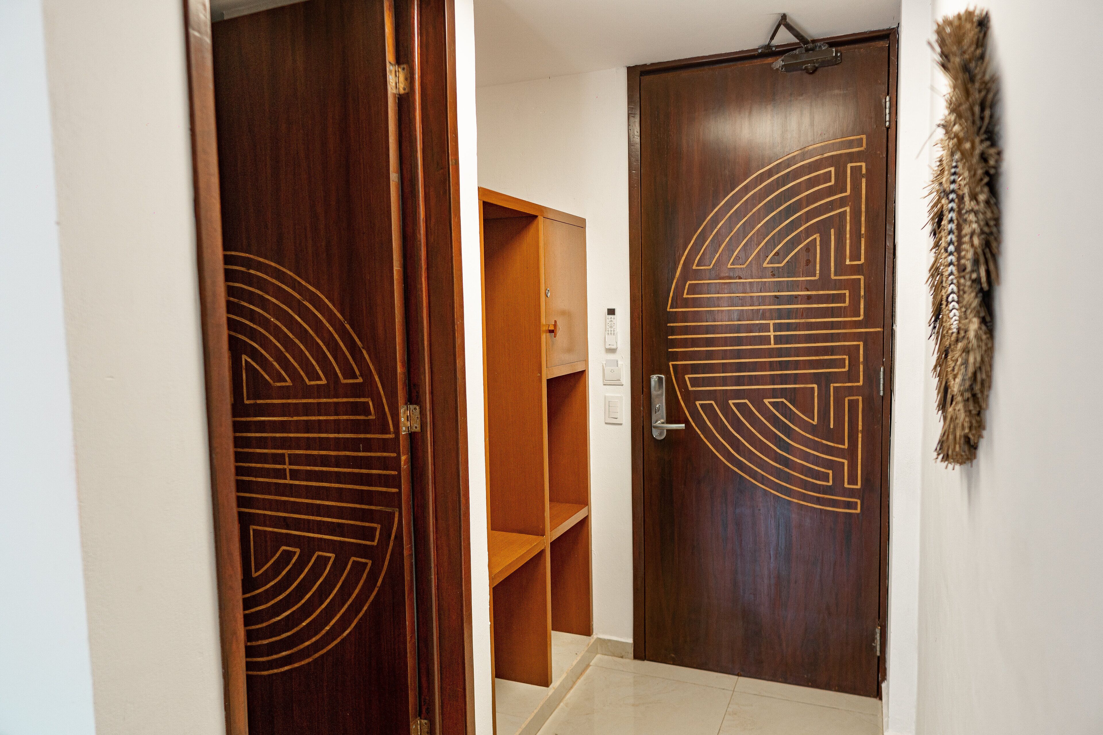 A wooden door with a geometric design, a wooden shelf unit, and a wall-mounted decorative item.