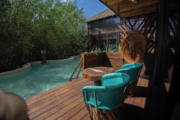 A wooden deck with a pool, turquoise chairs, and a thatched roof structure. - Akuazul Resorts Adults Only (Cancun)